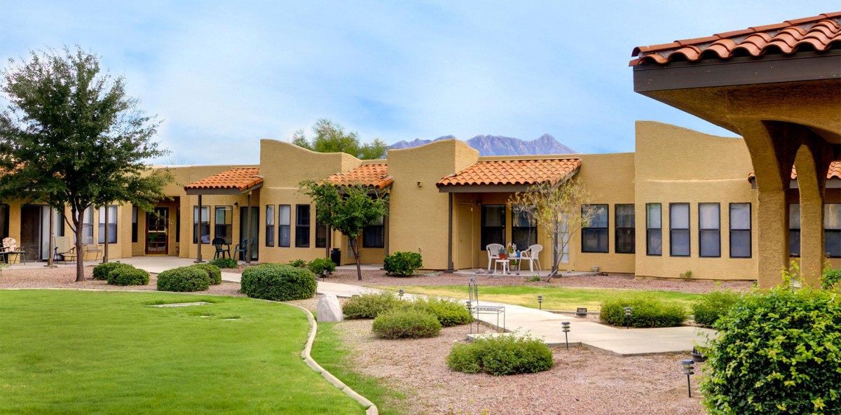 A southwestern-style house with a patio set against a backdrop of mountains and desert landscaping.