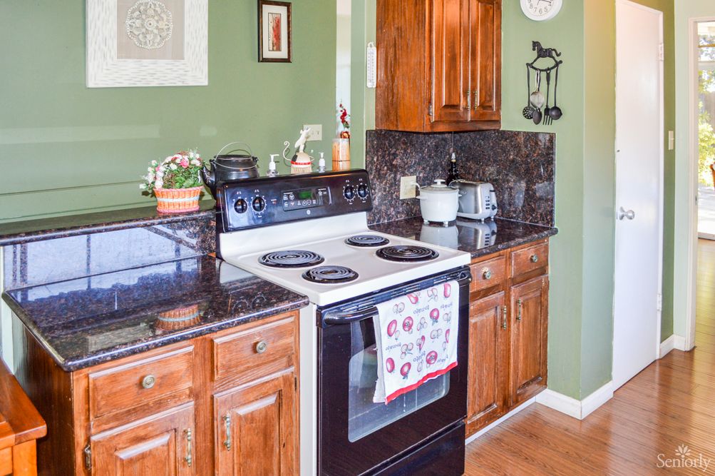 A cozy kitchen with wooden cabinets and a black stove against a green wall.