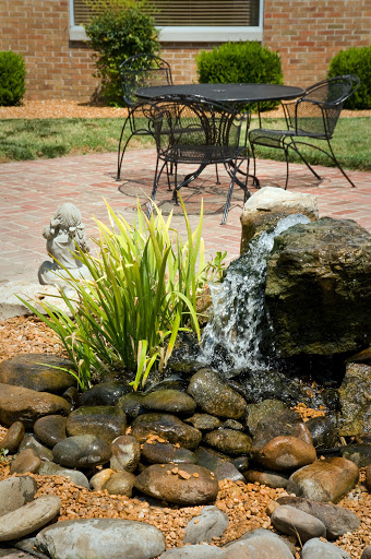 A serene garden scene featuring a small fountain surrounded by rocks and lush greenery, perfect for relaxation.