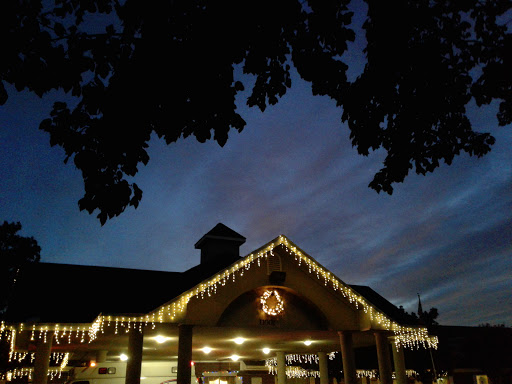 A cozy evening scene with holiday lights adorning a building under a twilight sky.
