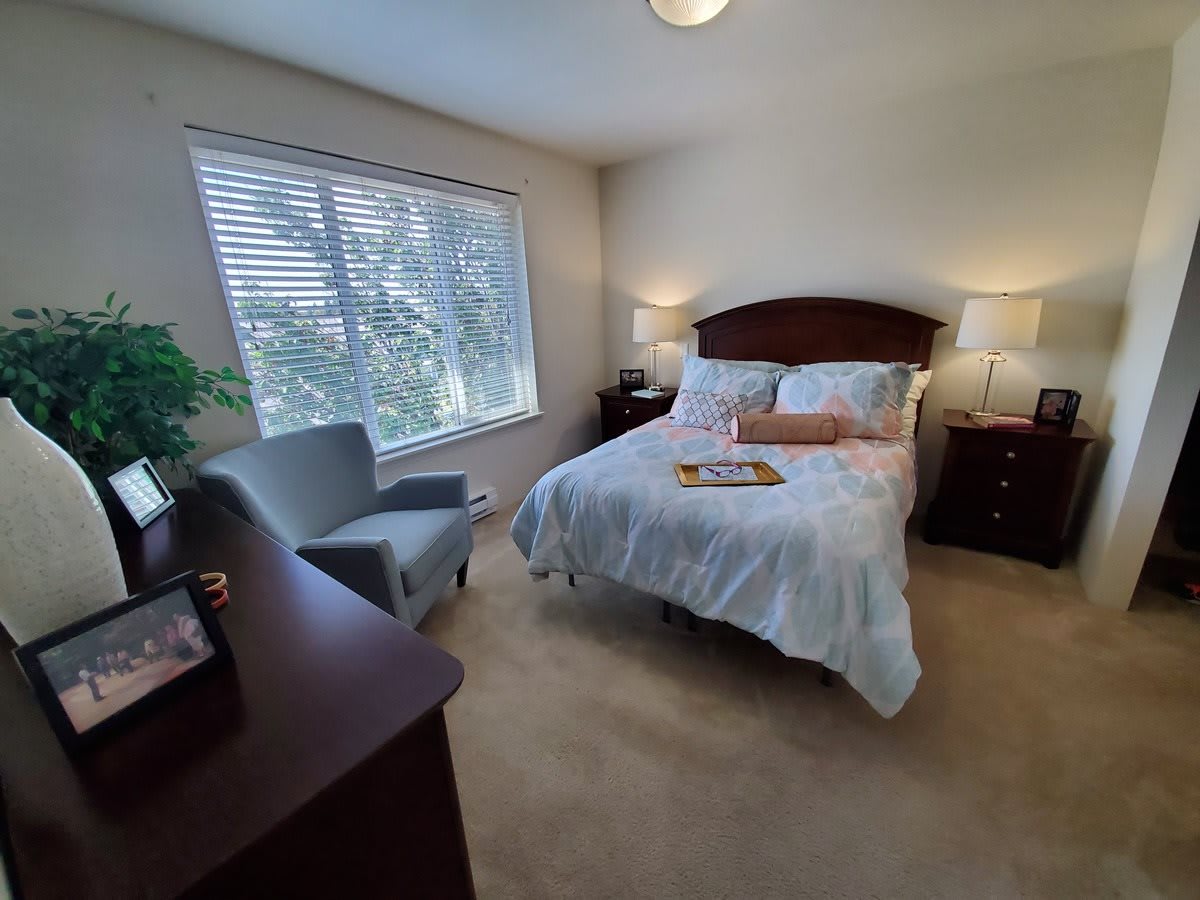 A cozy bedroom with a neatly made bed, bedside tables, and a large window.