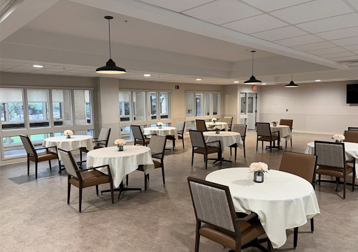 A modern dining area featuring neatly arranged tables and chairs, illuminated by stylish pendant lights.
