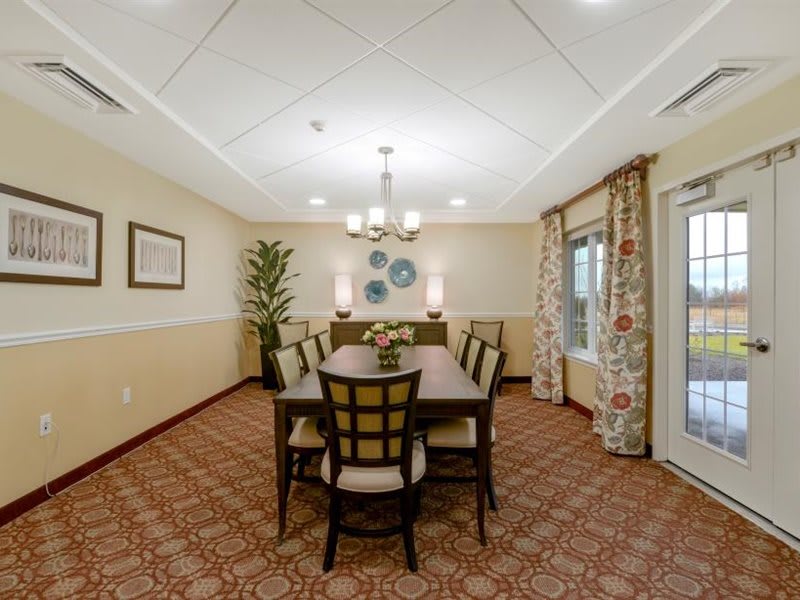 A well-decorated dining room with a central table, surrounded by chairs, featuring elegant lighting and tasteful decor.