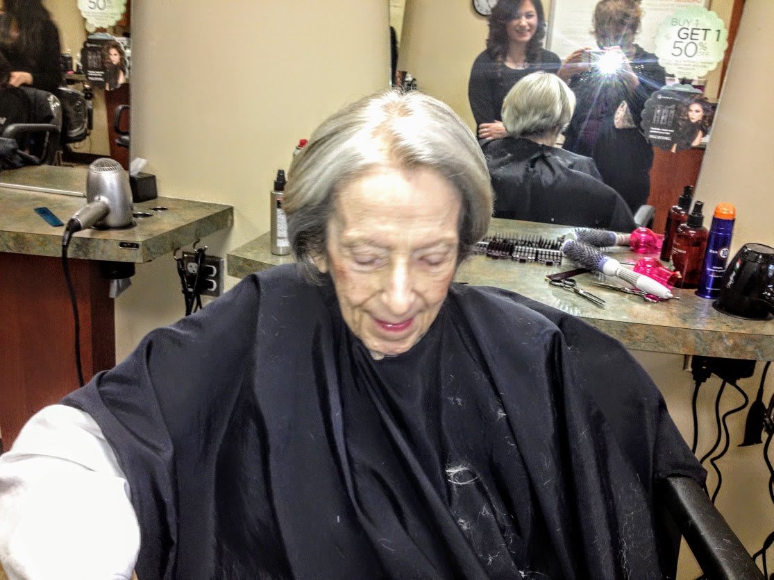 An elderly person in a hair salon getting their hair styled.