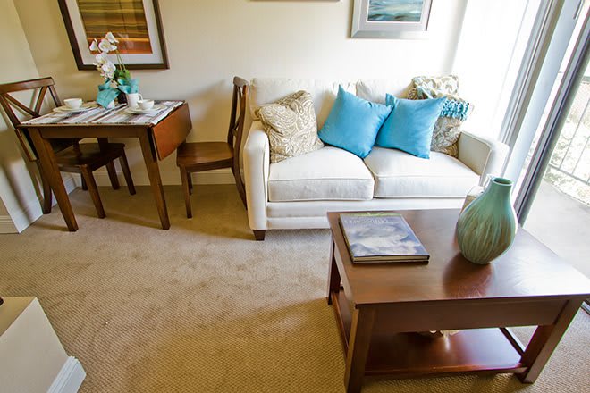 A cozy living room featuring a comfortable sofa adorned with blue cushions, a wooden coffee table, and classic decor.