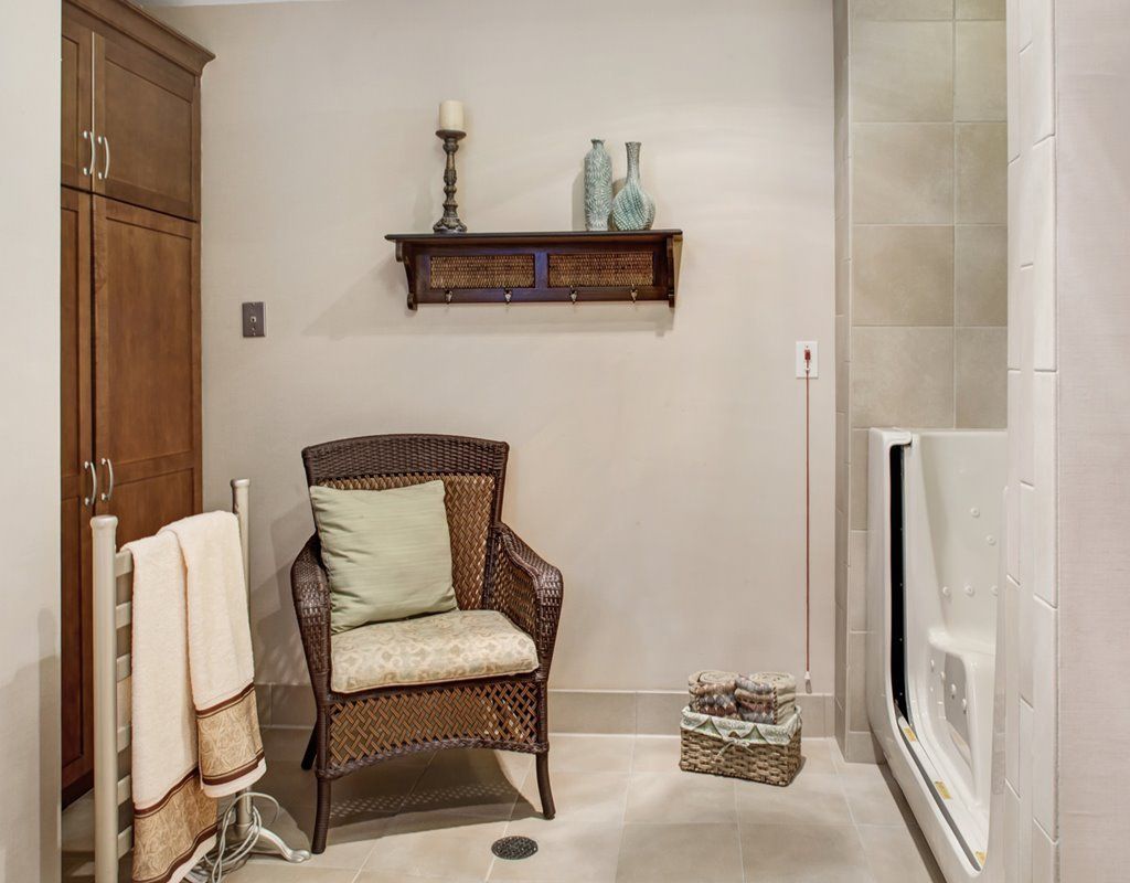 A cozy bathroom with wicker chair and decorative shelving.