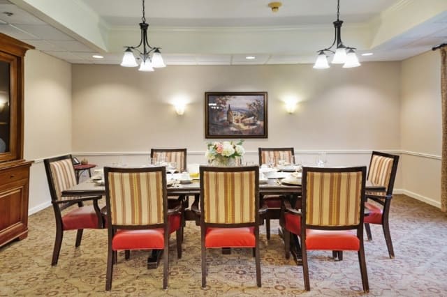 A well-appointed dining room with a large table, elegantly upholstered chairs, and warm lighting.