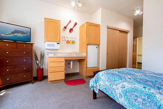 A cozy bedroom with wooden furniture, featuring a bed, cabinets, television, and decor.