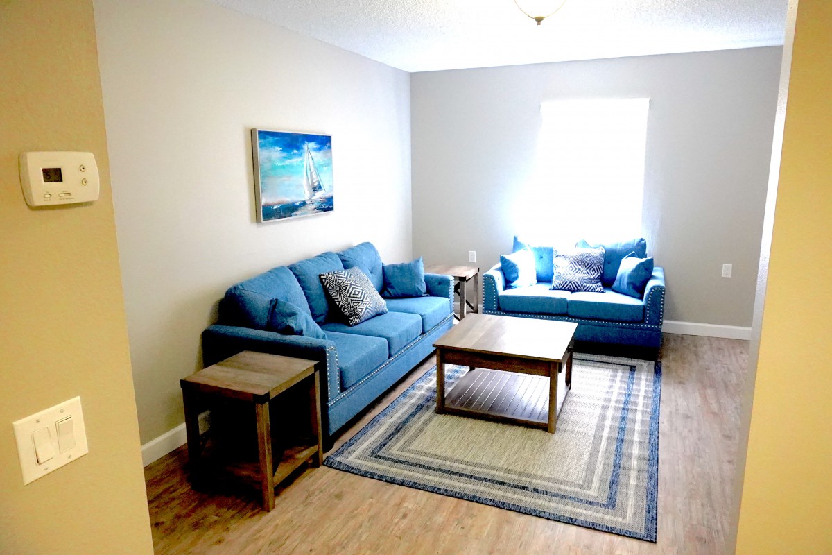 A cozy living room with blue sofas, a wooden coffee table, and wall art.