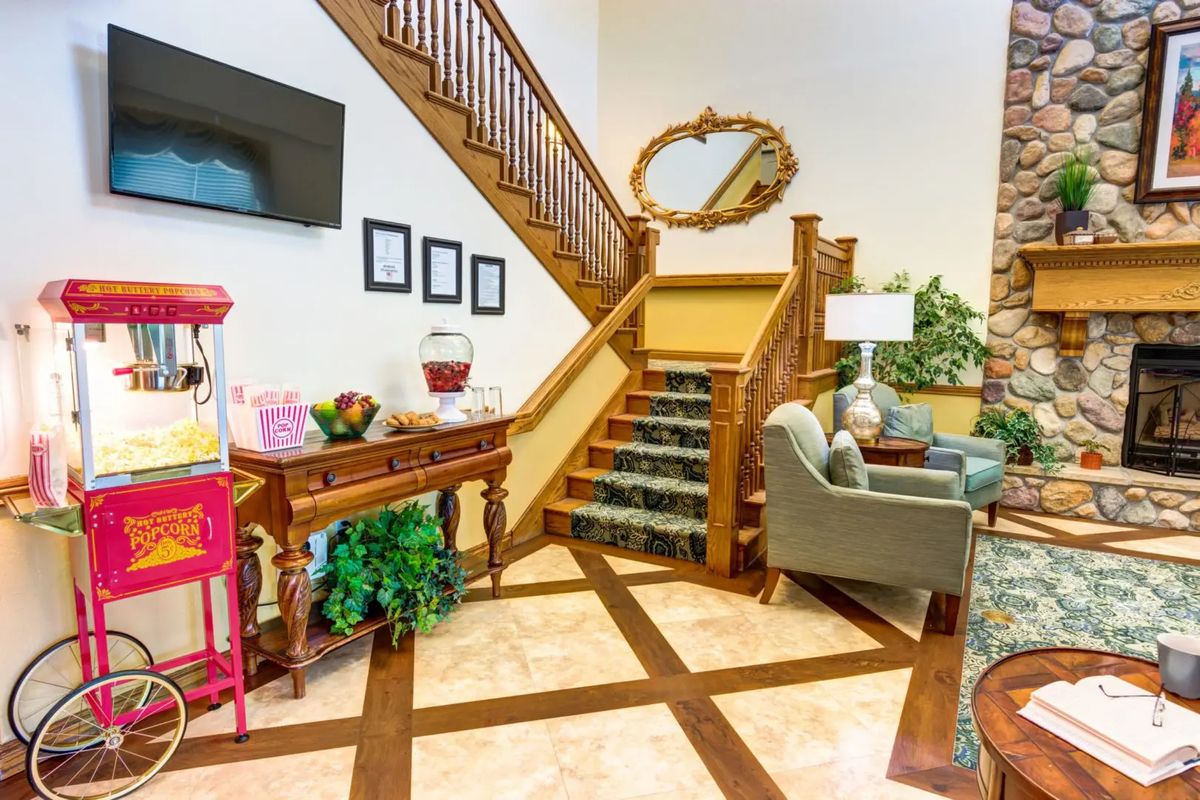 A cozy interior featuring a stylish staircase with wooden railings, comfortable seating, and decorative elements like a large mirror and plants.