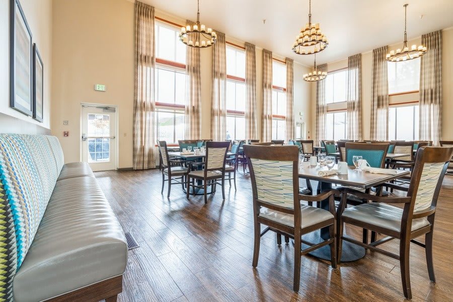 A spacious dining area with high ceilings and large windows, featuring elegant tables and chairs.