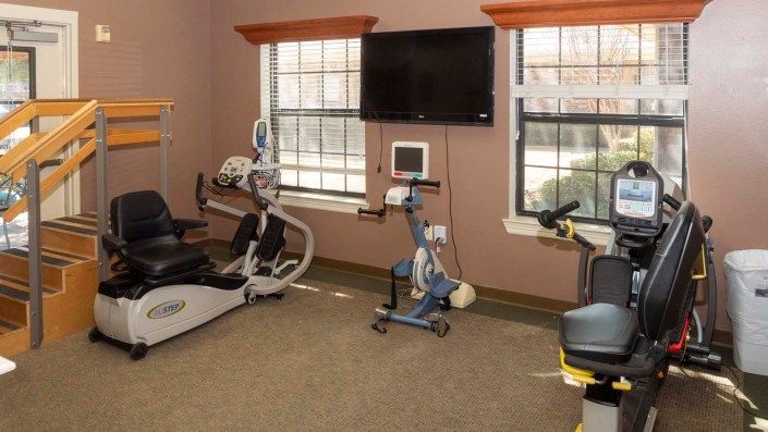 A small fitness room with exercise equipment including stationary bikes and an elliptical machine.