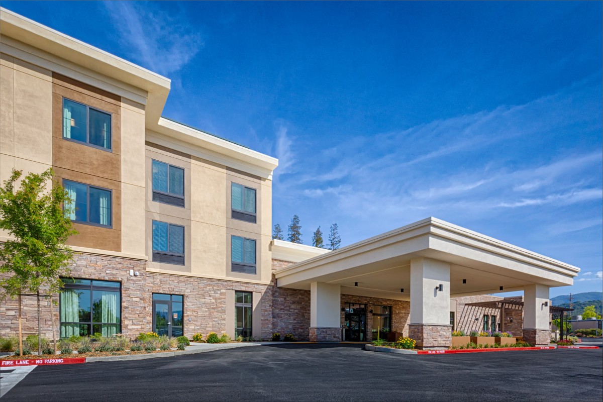 A modern hotel building with a welcoming entrance under clear blue skies.
