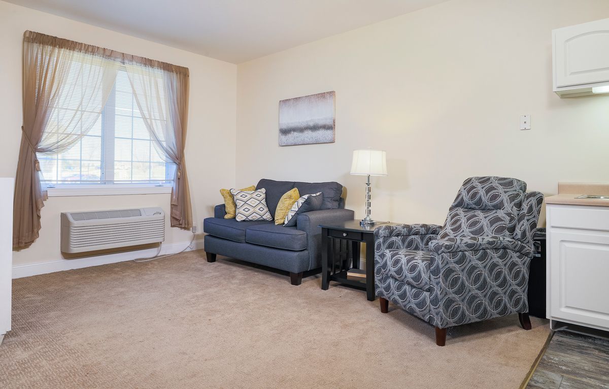 A cozy living room with a sofa, armchair, and lamp.