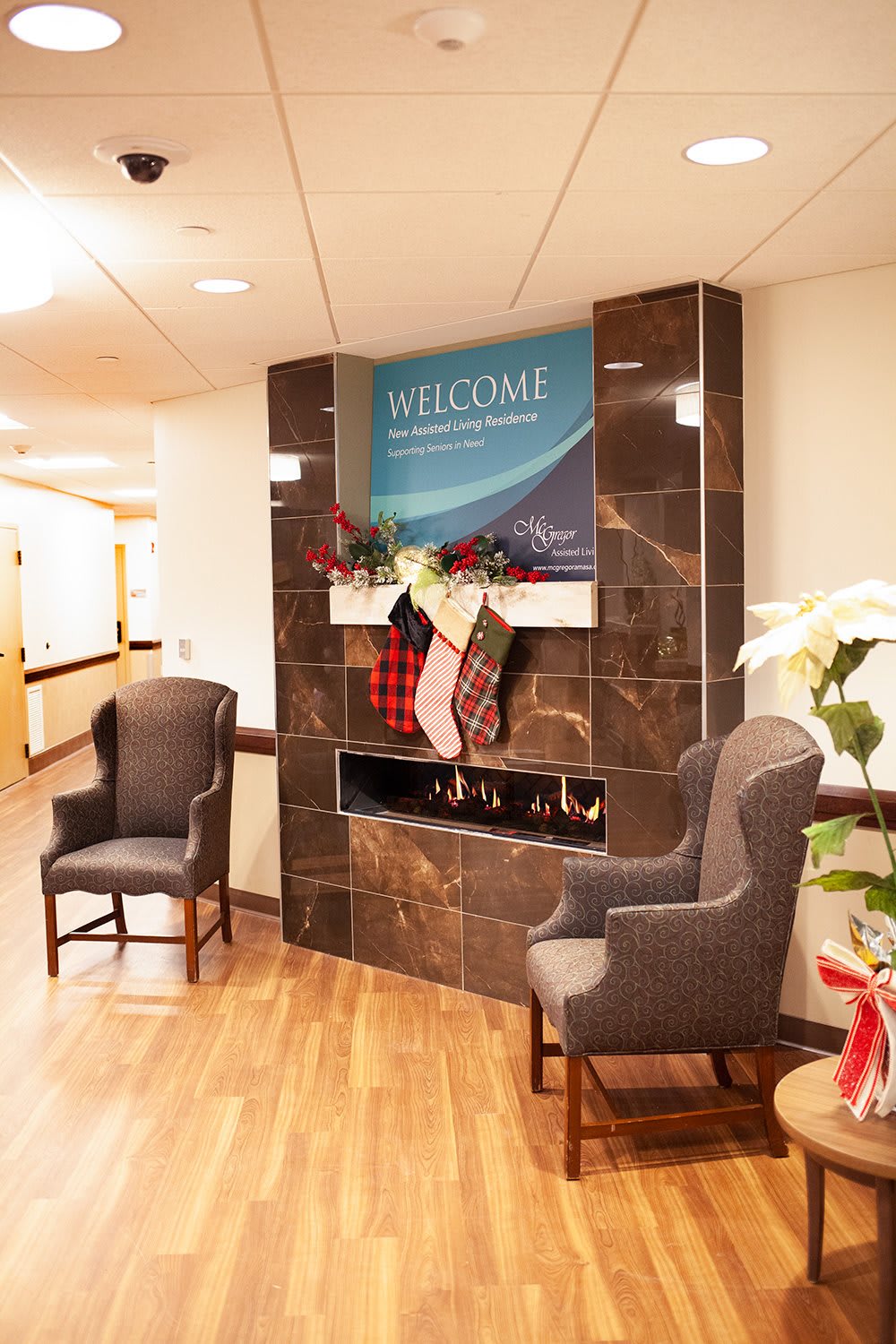 A hospital waiting area with decorated fireplace and chairs.