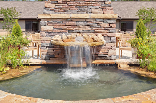 A serene waterfall cascading over a stone fountain, creating a peaceful outdoor atmosphere.