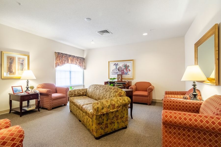 A cozy living room with a sofa, several chairs, and a large window.