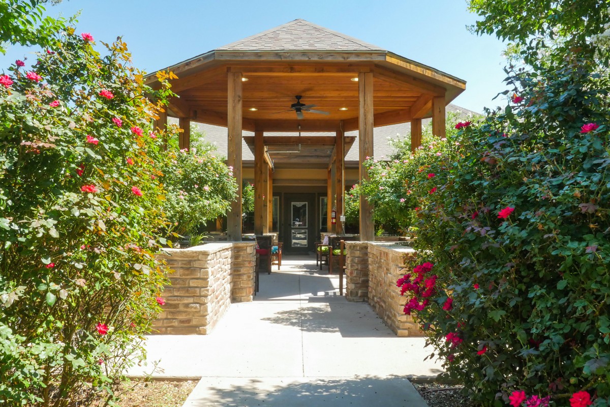 A beautifully landscaped pathway leads to a wooden gazebo surrounded by vibrant flowers.