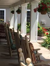 A sunny porch with wooden rocking chairs and colorful flowers.
