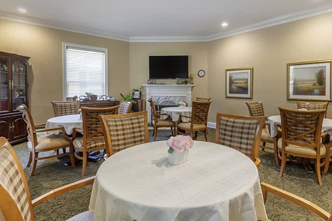 A cozy dining room with multiple tables and chairs, featuring a television and tasteful decor.