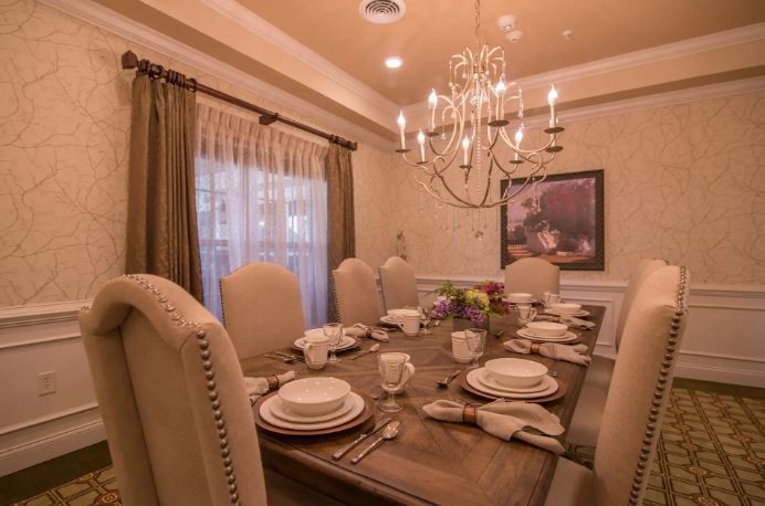 An elegantly set dining room with a chandelier and complete table settings.