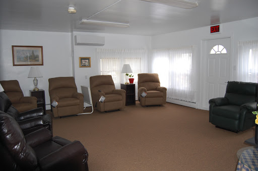 A cozy living room featuring comfortable recliners, a lamp, and ample natural light.