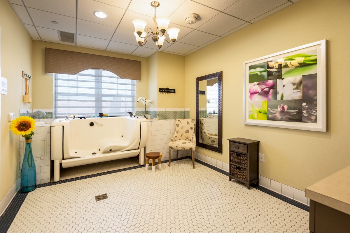 A spacious bathroom with a walk-in bathtub, decorative mirror, and elegant lighting.