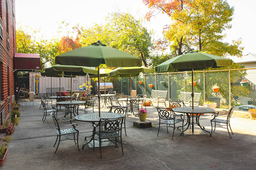 A serene outdoor patio with green umbrellas, perfect for enjoying a meal amidst the beautiful fall colors.