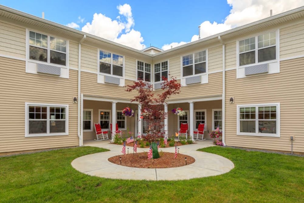 A residential building with a landscaped courtyard featuring a central tree and surrounding seating.