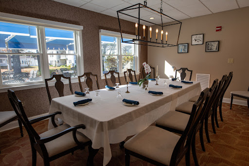 A beautifully set dining room with a modern chandelier and natural light streaming in through the windows.