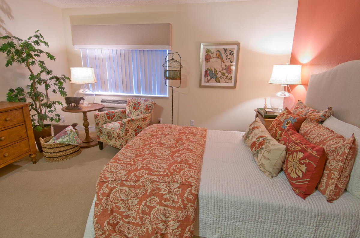 A cozy, well-decorated bedroom with patterned bedding and elegant lighting.