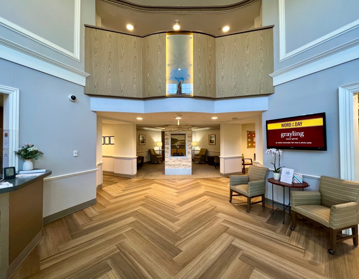 A modern hotel lobby with wooden flooring and seating areas.