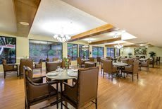 A well-appointed dining area with neatly arranged tables and chairs, featuring large windows and modern lighting fixtures.