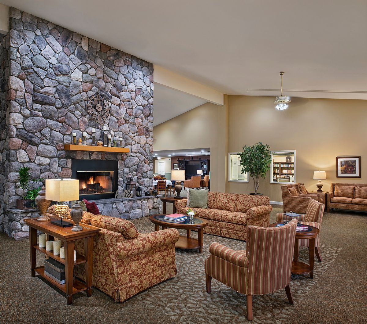 A cozy lounge area featuring comfortable seating, a stone fireplace, and warm lighting.