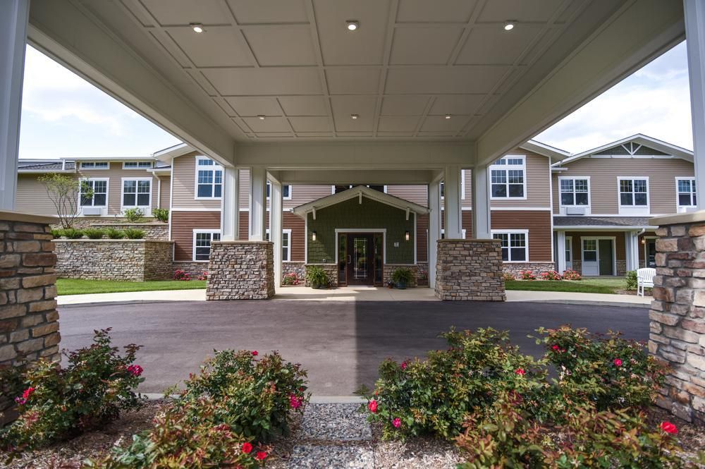 A modern building entrance with landscaped flower beds and stone accents.
