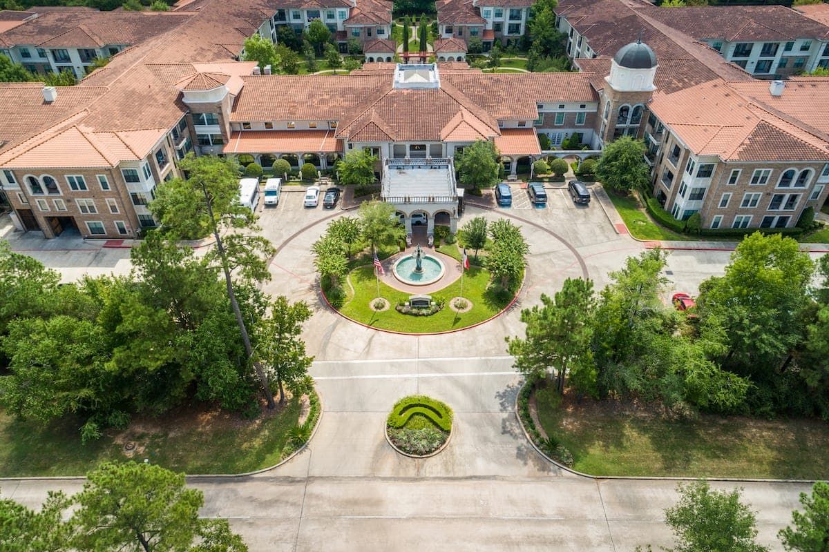 An aerial view of a large building complex with a central fountain and landscaped driveway.