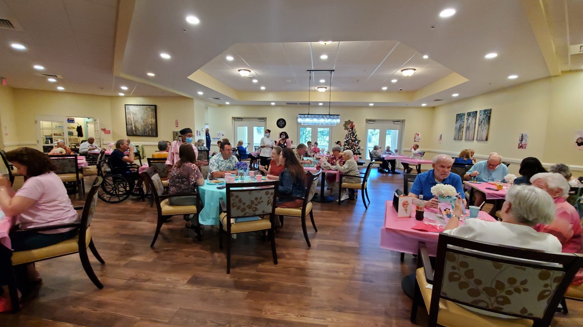 A group of people enjoying a gathering in a decorated indoor space with tables and chairs.