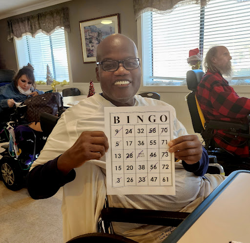 A joyful participant holding up a bingo card during a fun community game.