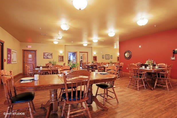 A cozy restaurant dining area with wooden tables and chairs, lit by warm lighting.