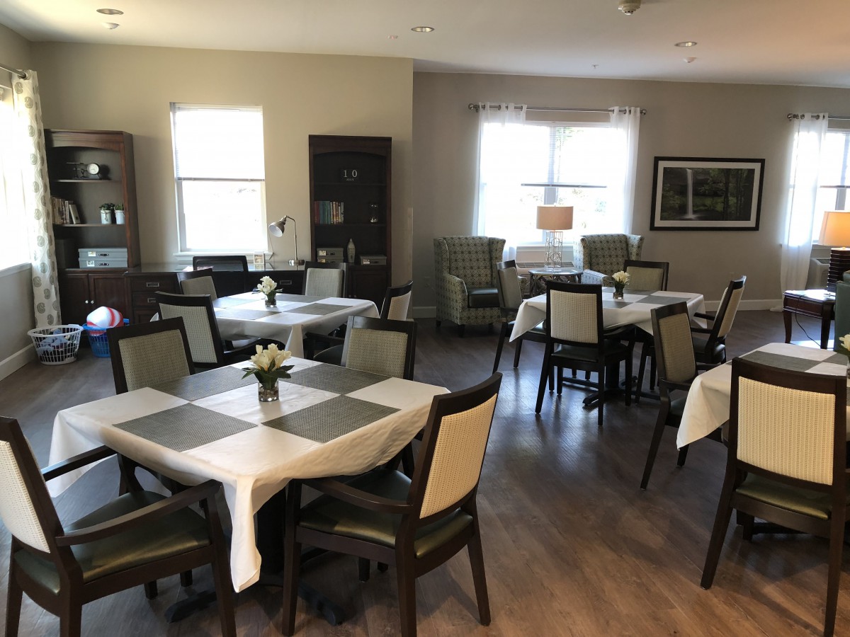 A cozy dining area with neatly arranged tables and chairs, featuring natural light from the windows.