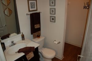 A neatly organized bathroom featuring a sink, toilet, and wall decor.