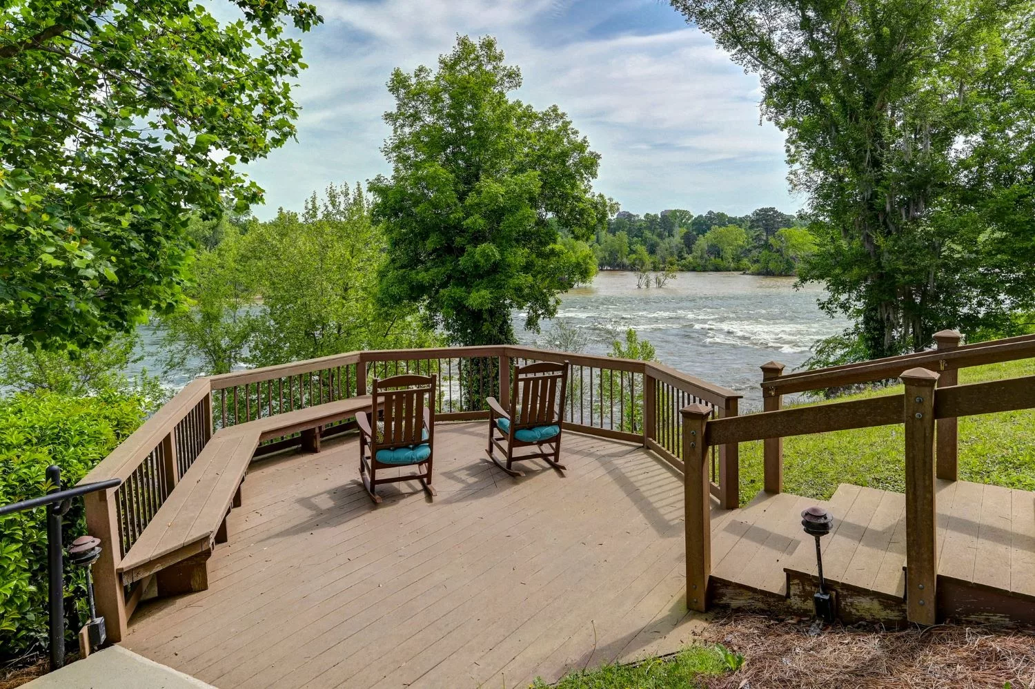 A serene deck overlooking a river, surrounded by lush greenery.