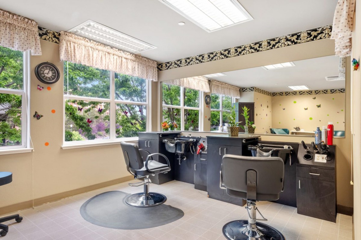 A well-lit salon interior with styling chairs and large windows.