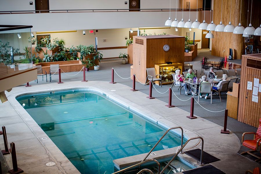An indoor pool located in a hotel lobby with adjacent dining and seating areas.