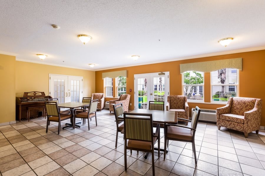 A spacious and well-lit common area with tables and chairs arranged for social gatherings.