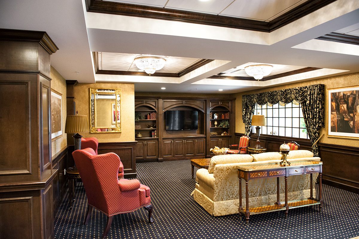 A classic-style living room featuring comfortable seating, elegant woodwork, and a large television.