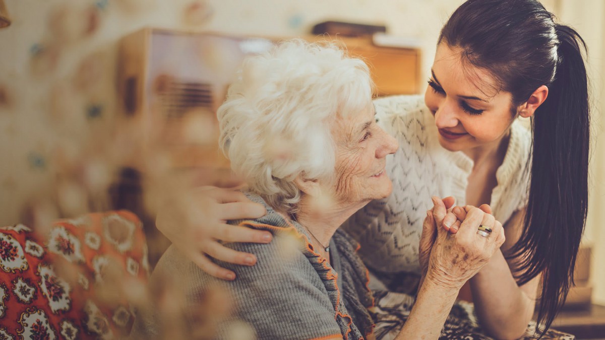 A caring moment between a young woman and an elderly person, highlighting affection and support.