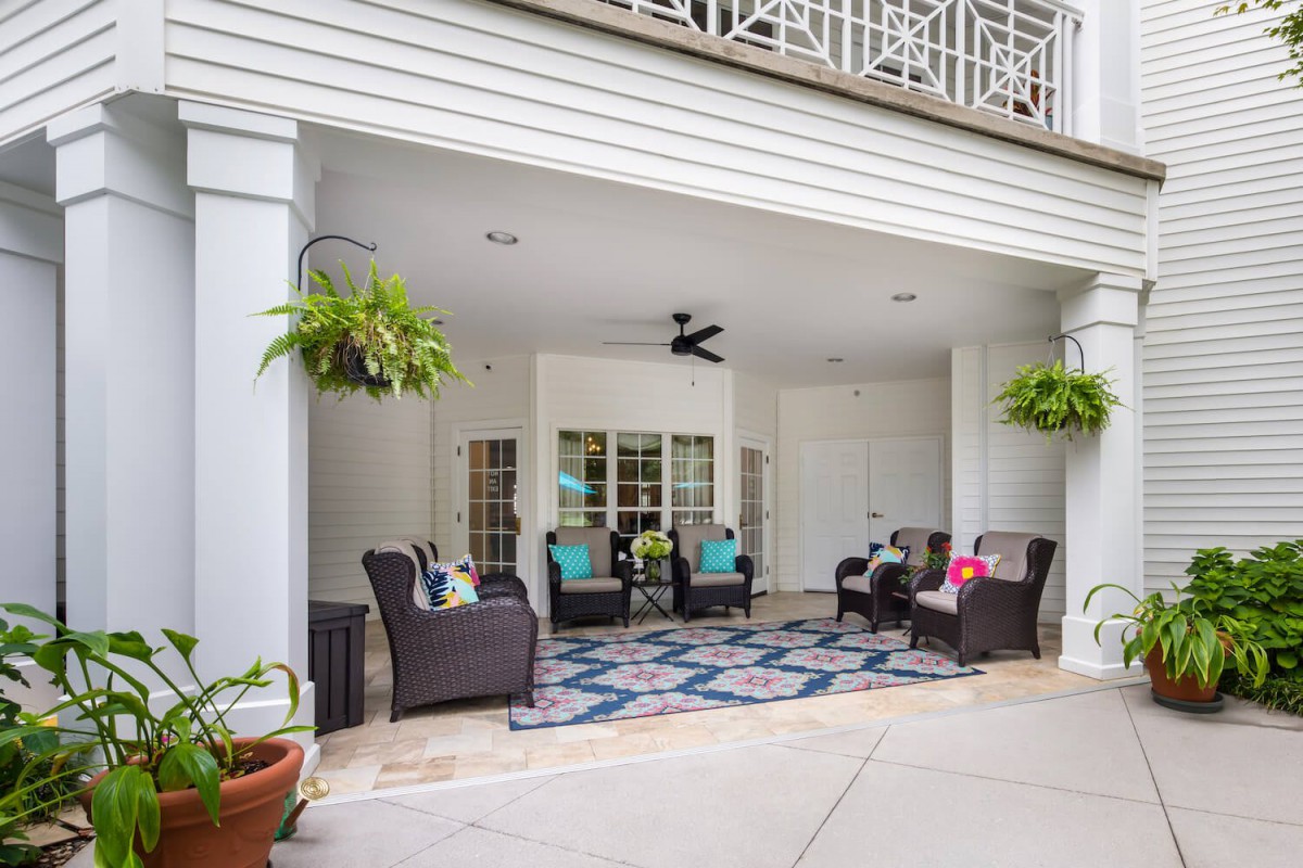 A cozy outdoor patio with comfortable seating, decorative plants, and a ceiling fan.
