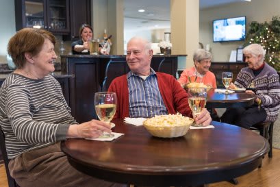 A group of seniors enjoying wine and snacks while socializing indoors.