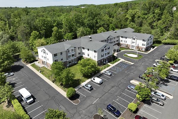 Aerial view of an apartment complex surrounded by trees with a parking lot in front.